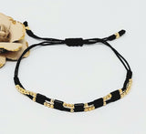Double adjustable thread bracelet with gold plate balls. Black